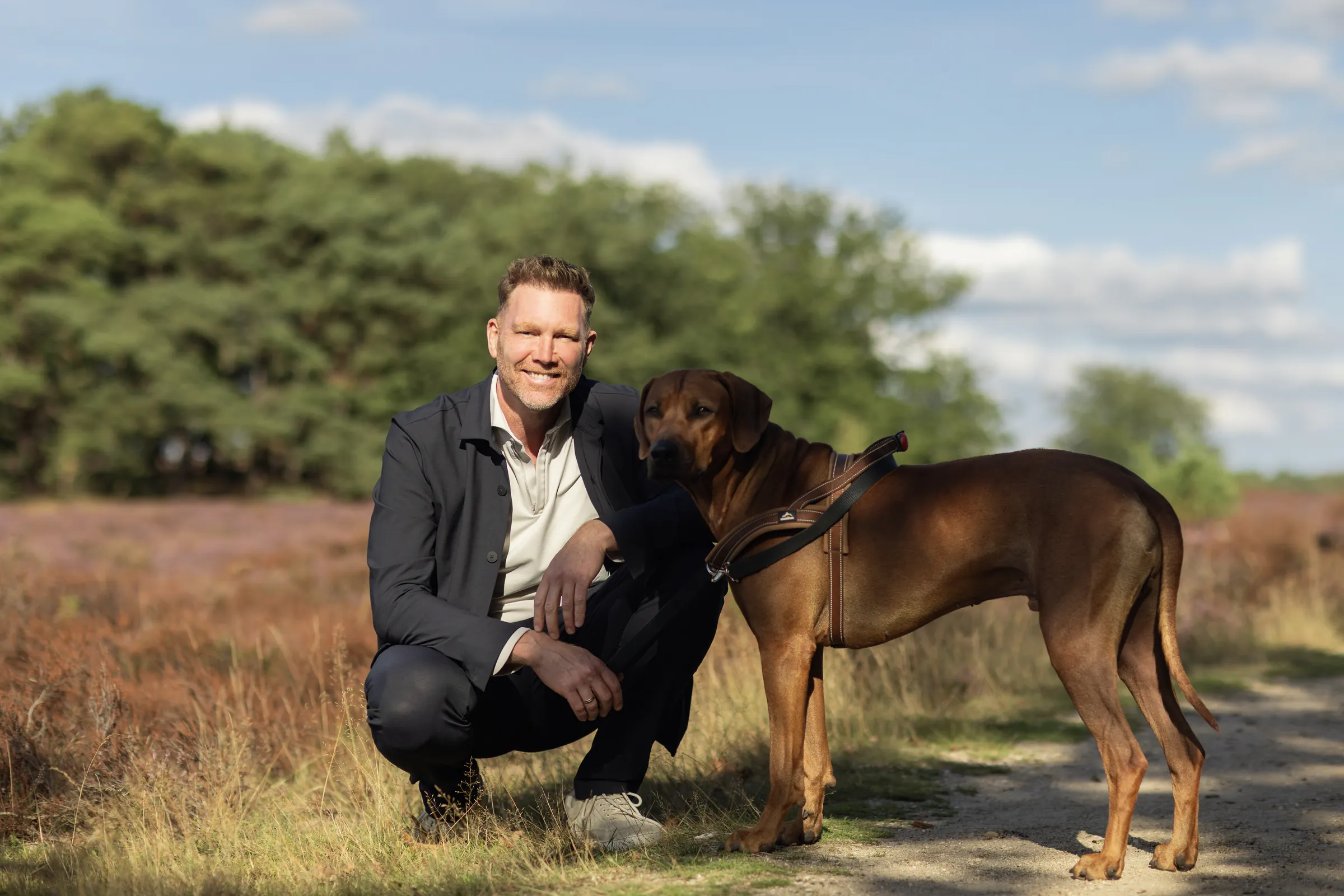 Sipke Jan Bousema gehurkt naast zijn Rhodesian Ridgeback op de heide